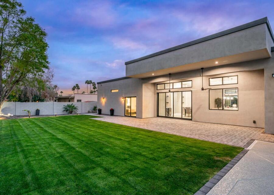 Modern Scottsdale home at dusk with manicured lawn and lit interior